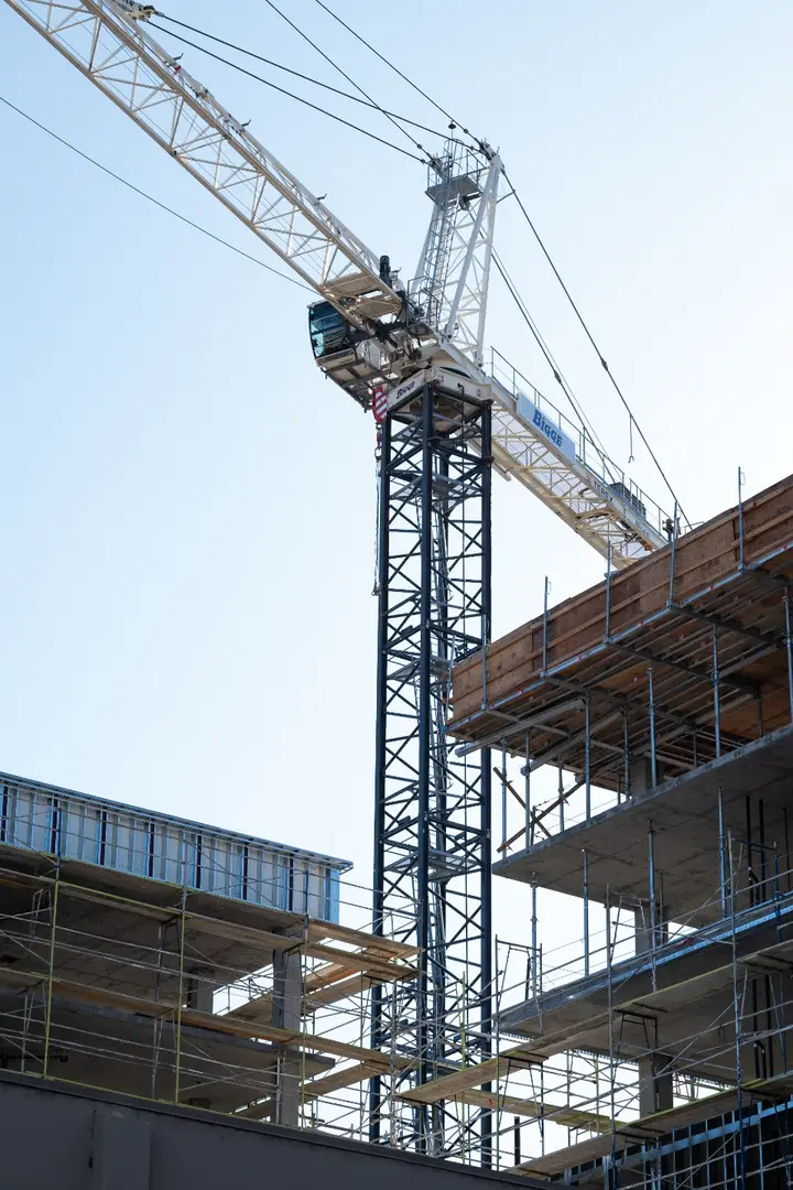 Grúa torre junto a una estructura en construcción, contra el cielo